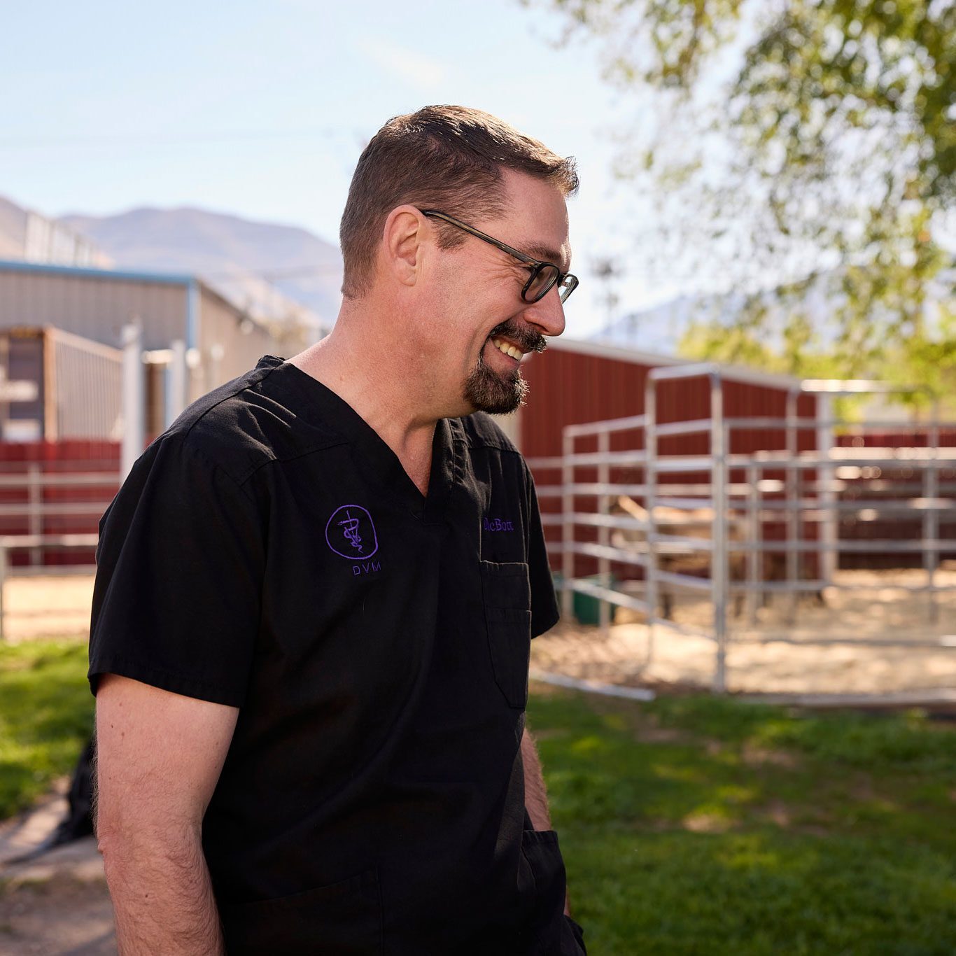 smiling male veterinarian standing outside and looking down to the right